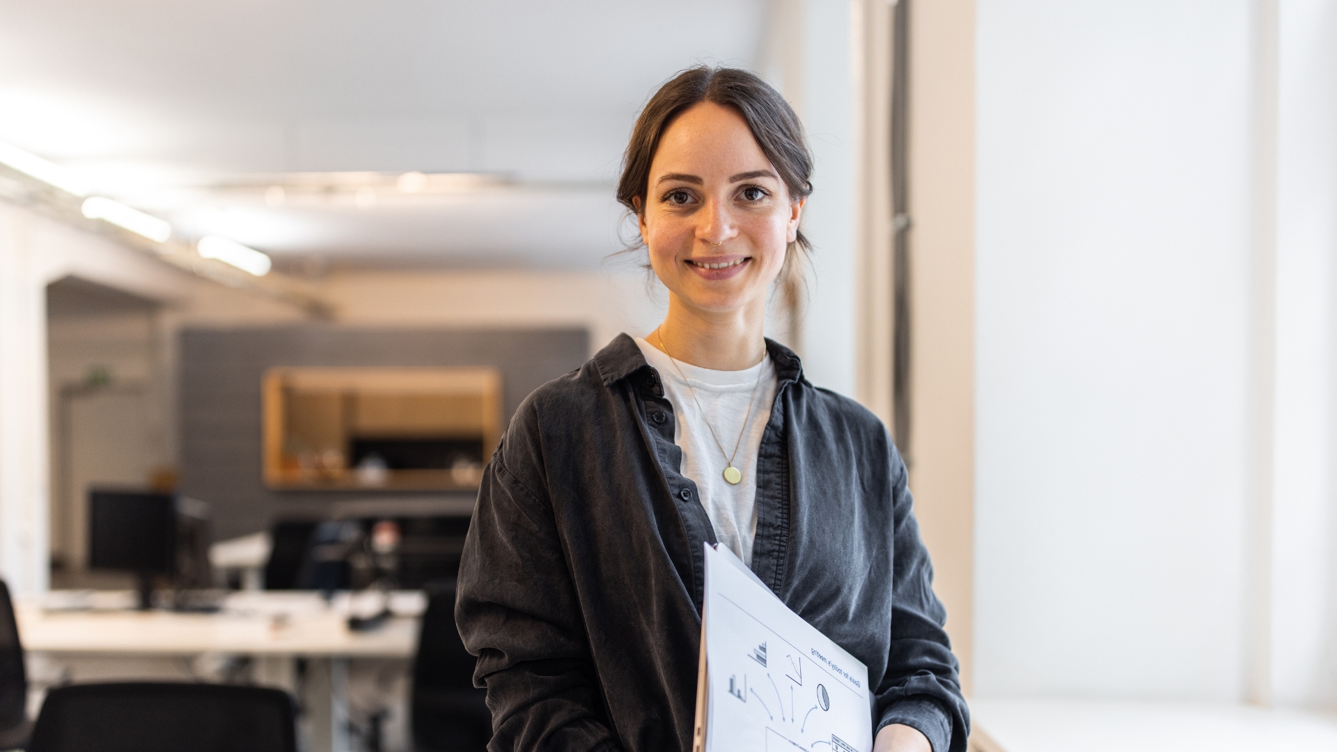 Eine Frau steht lächelnd in einem Arbeitsraum