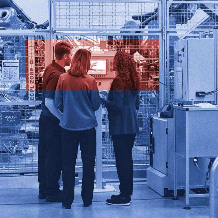 Drei Personen stehen vor einer High-Tech-Produktionsanlage und reden miteinander. Auf dem Bild liegt ein blauer Filter, die drei diskutierenden Personen sind durch ein Orangenes Rechteck hervorgehoben.