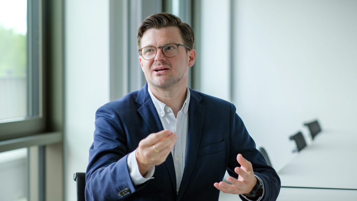 Prof. Tobias Kämpf gestikuliert in einer Gesprächssituation im Beprechungsraum der University of Labour.