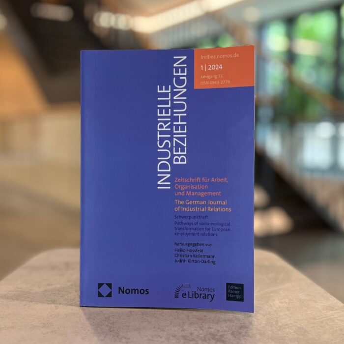 Im Mittelpunkt und Vordergrund des Bildes steht der Sonderband der Industriellen Beziehungen. Im Hintergrund ist verschwommen das Foyer der University of Labour erkennbar.