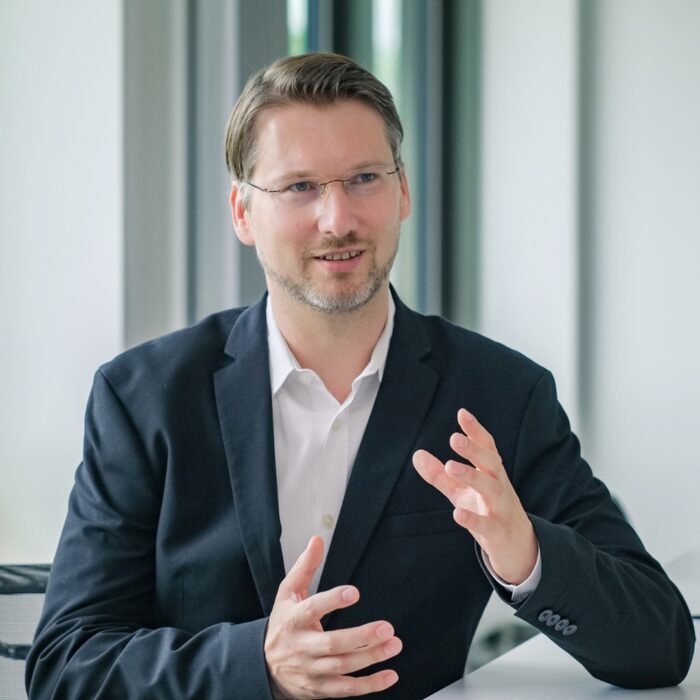 Philipp Donath befindet sich in einem Gespräch im Besprechungsraum der University of Labour. Er gestikuliert dabei mit den Händen.