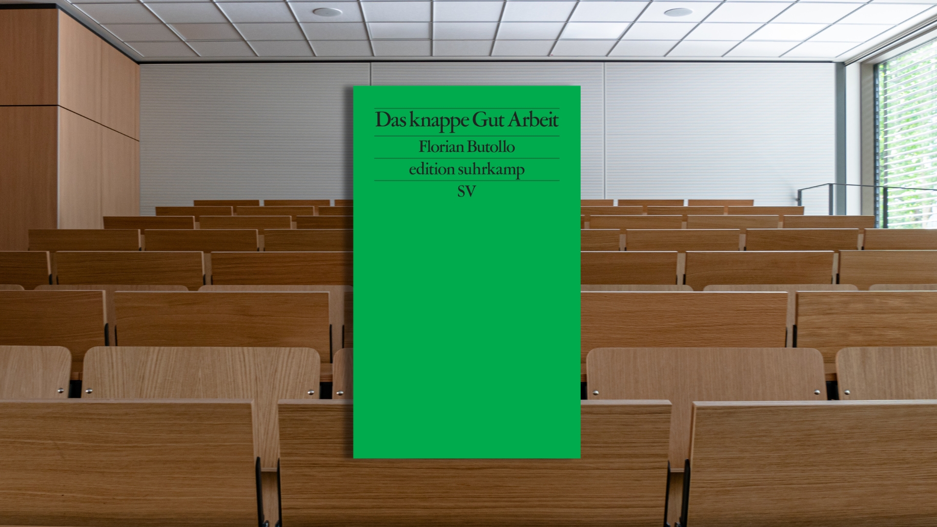 Grünes Buchcover mit dem Titel "Das knappe Gut Arbeit" von Florian Buttolo, platziert vor einem Hörsaal.